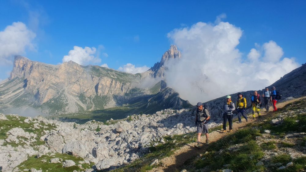 Hikers in front of the Dolomites peaks of Croda da Lago, heading south on Alta Via 1 trek