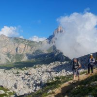 Hikers in front of the Dolomites peaks of Croda da Lago, heading south on Alta Via 1 trek