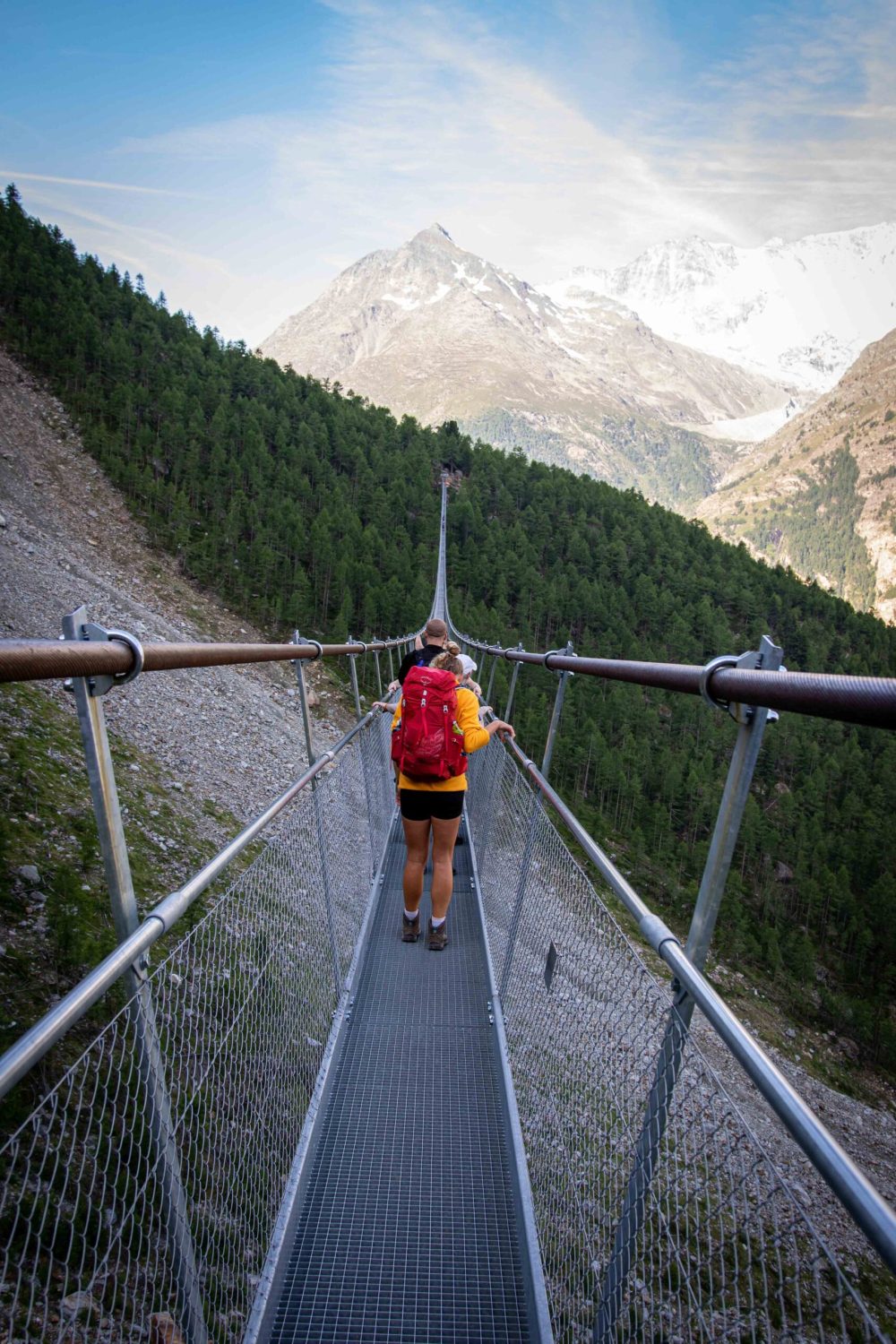 people walking across a long suspension bridge