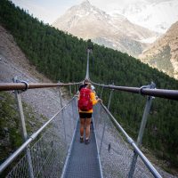 people walking across a long suspension bridge