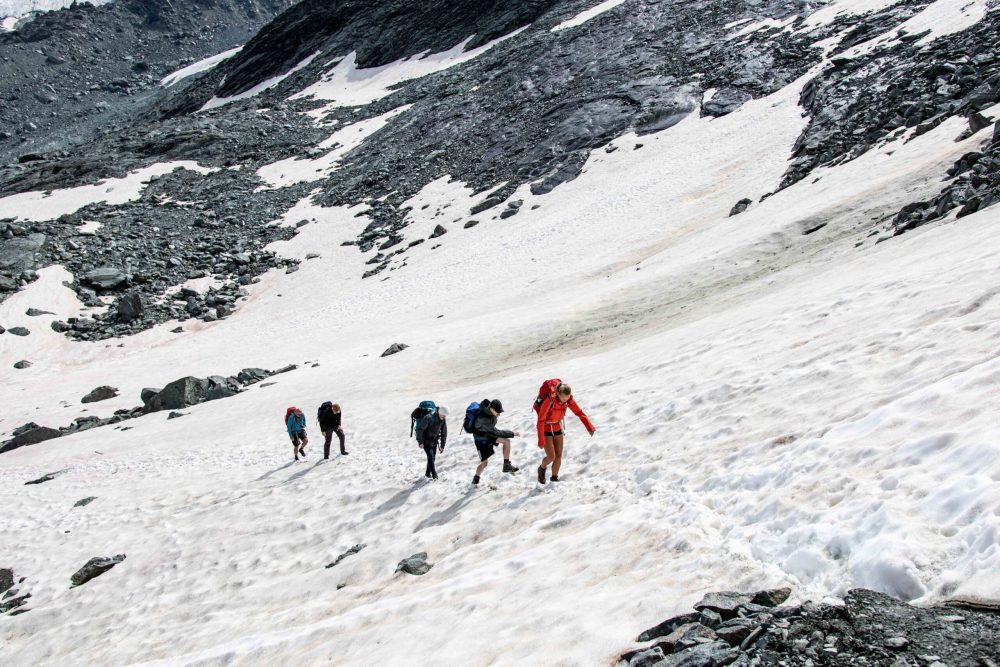 Hikers crossing a snow field on Tour du Mont Blanc trail in early summer