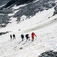 Hikers crossing a snow field on Tour du Mont Blanc trail in early summer