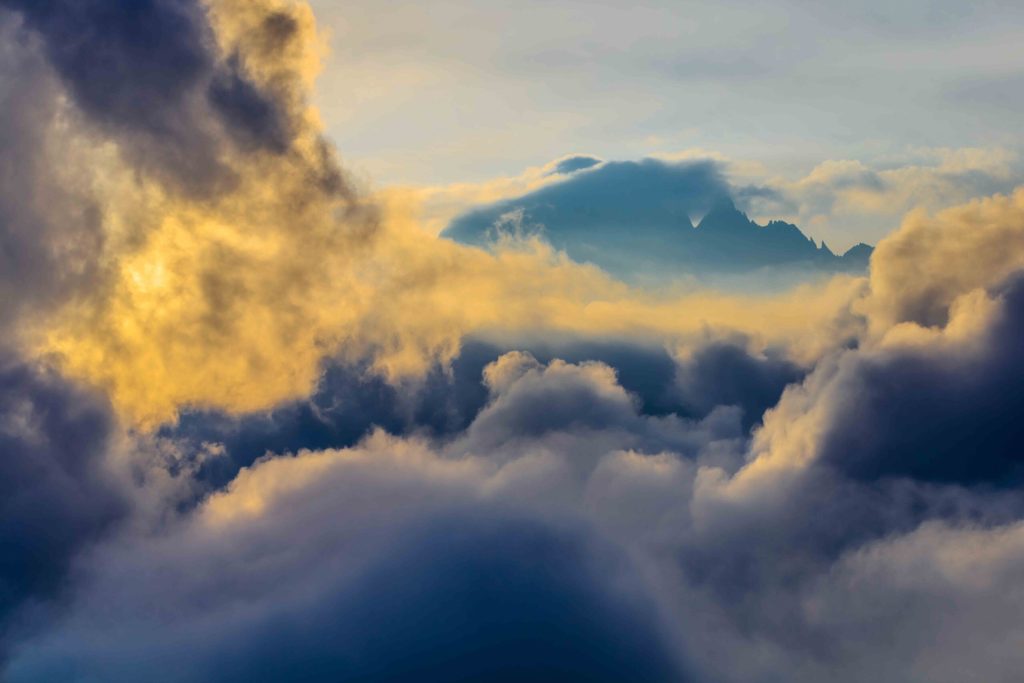 Clouds coloured orange with sunrise with the Mont Blanc summit in the background. View from Lac Blanc, France