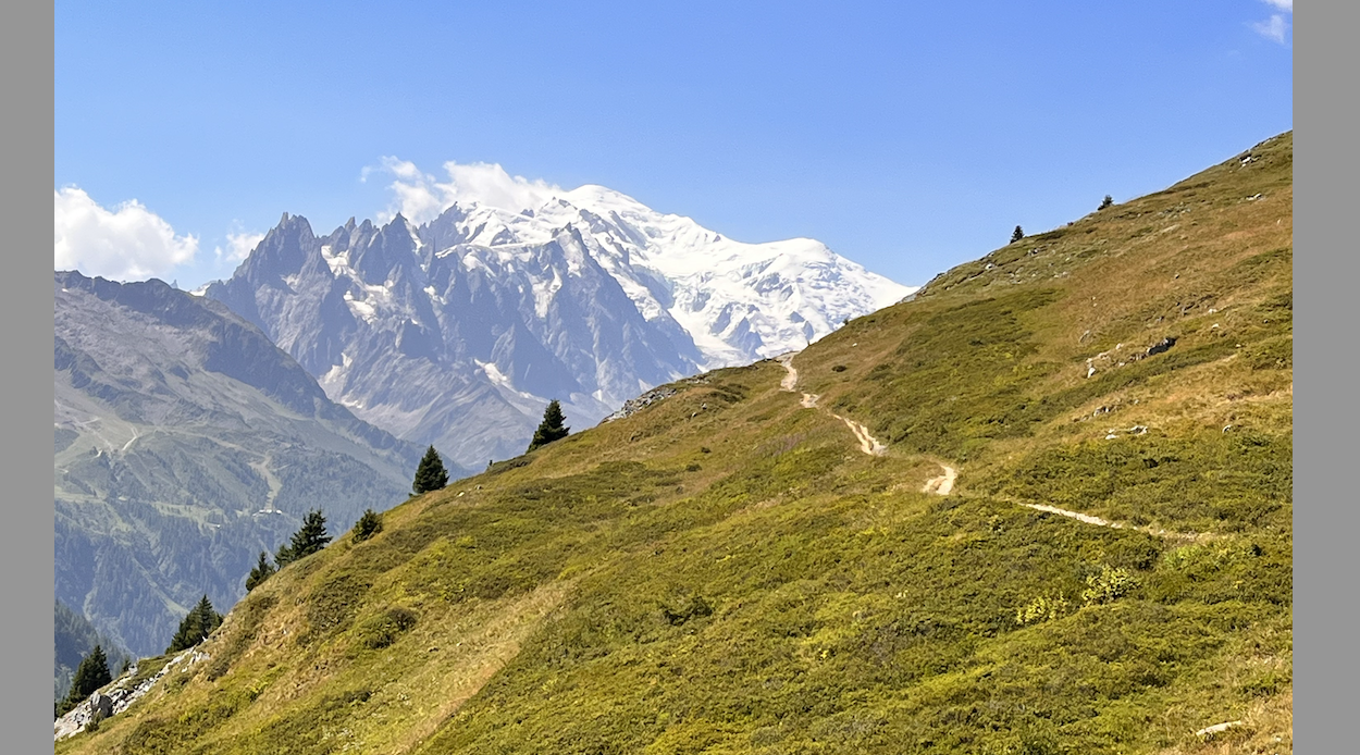 Mont Blanc viow and hikers on a high trail section of TMB