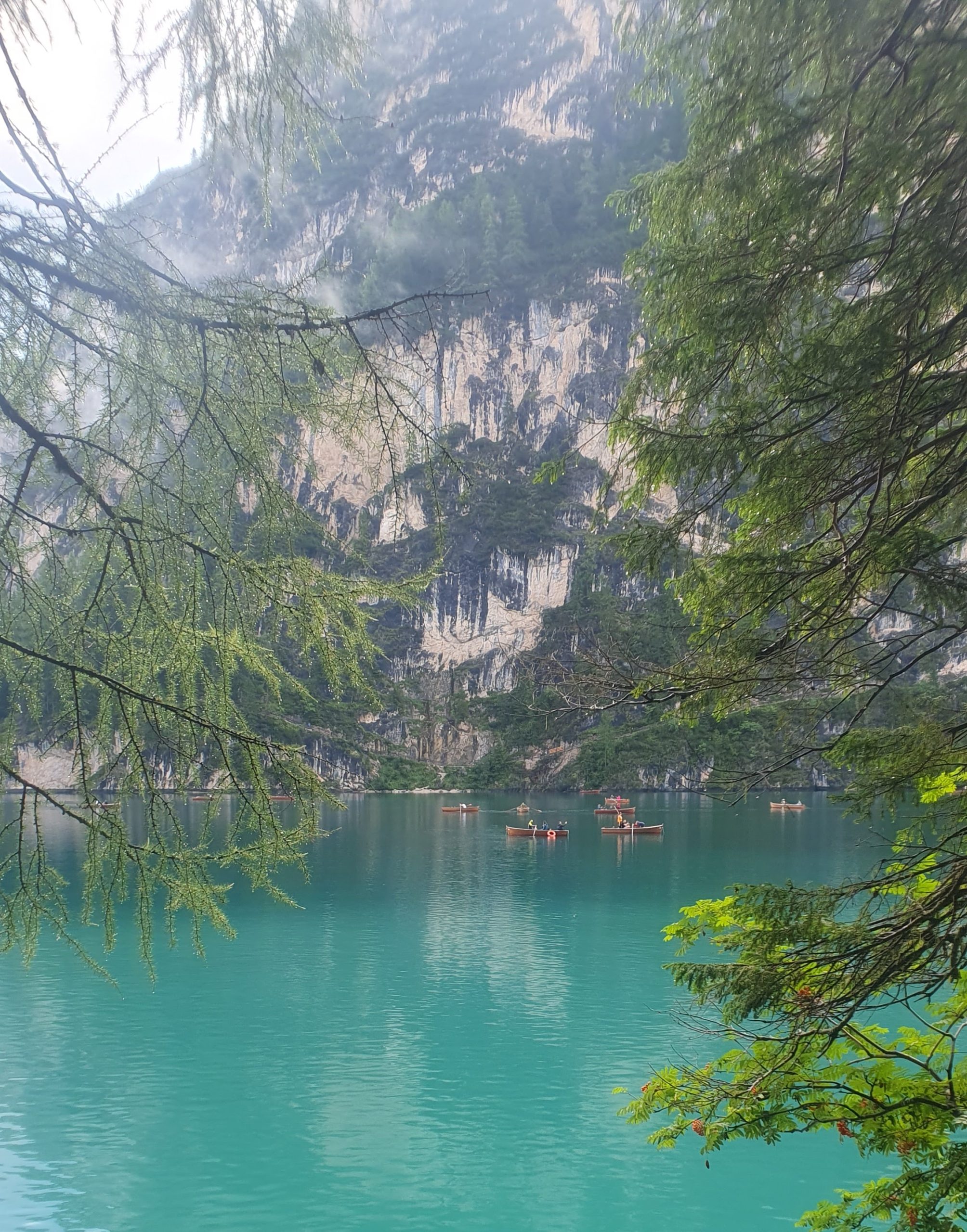 Rowing boats floating on Lago di Braies turquoise water on the starting date of Alta Via trek