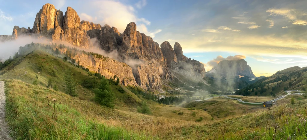 Alta Via 2 hiking grassy trail with Dolomites Sella summits coloured yellow in sunset