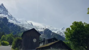 Snowy Mont Blanc seen from green Chamonix village with wooden chalets in May 2026