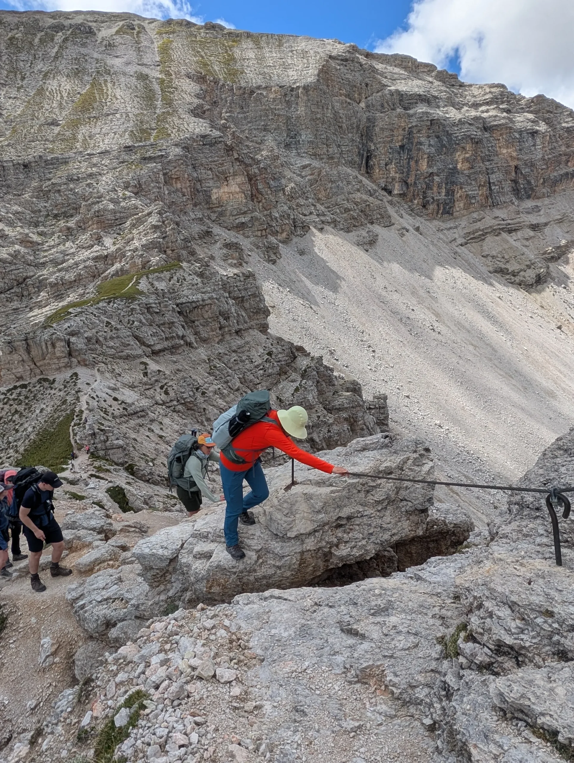 Brightly dressed hiker on an equipped mountain trail on the AV2 of the dolomites